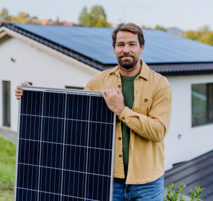 SHSEIP technician carrying a solar panel at a home installation